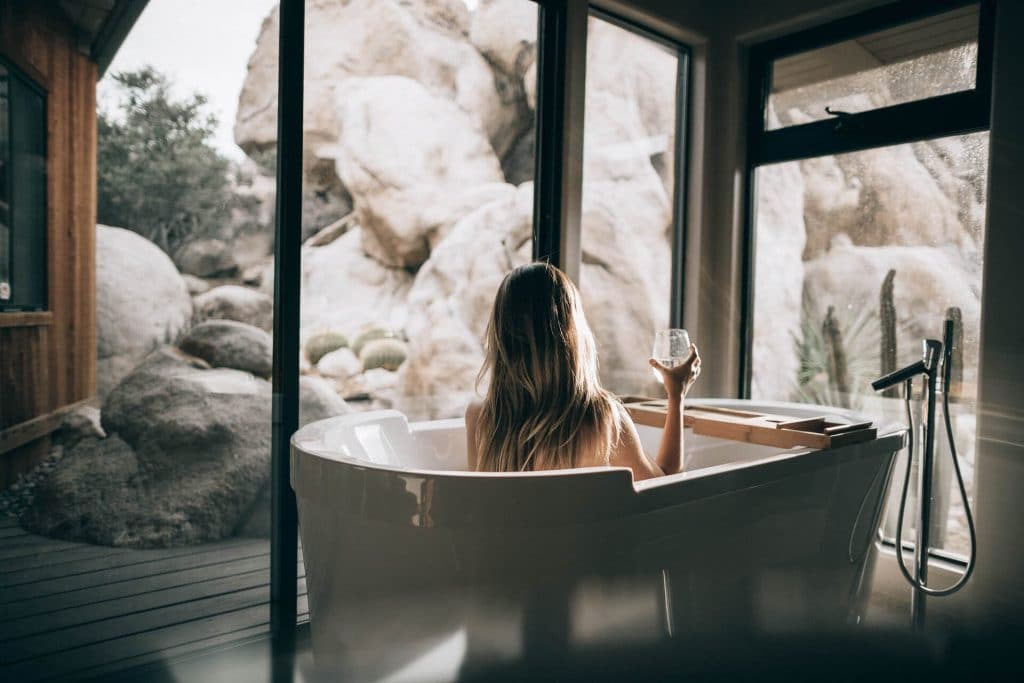 Woman in a bathtub looking at the stones through the glass windows